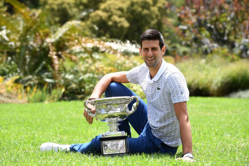 Novak Djokovic poses for photographs with the Norman Brookes Challenge Cup trophy at the Royal Botanical Gardens in Melbourne