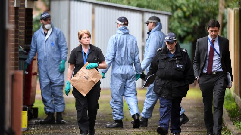 Police officers conduct a search of a bail hostel in south London 