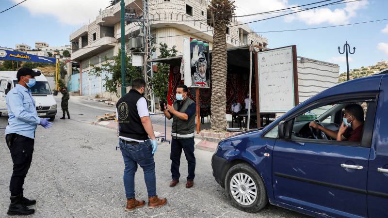 Palestinians close two West Bank cities after virus spike