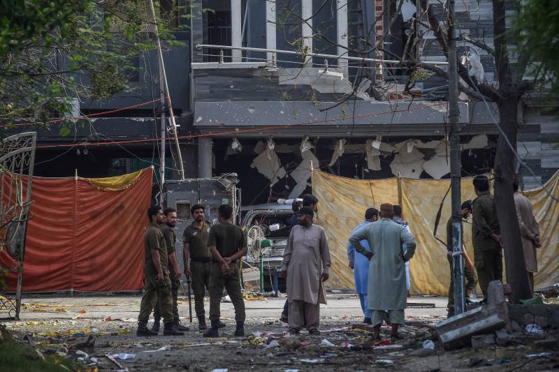 Investigators stand near the site of a bomb blast in Lahore