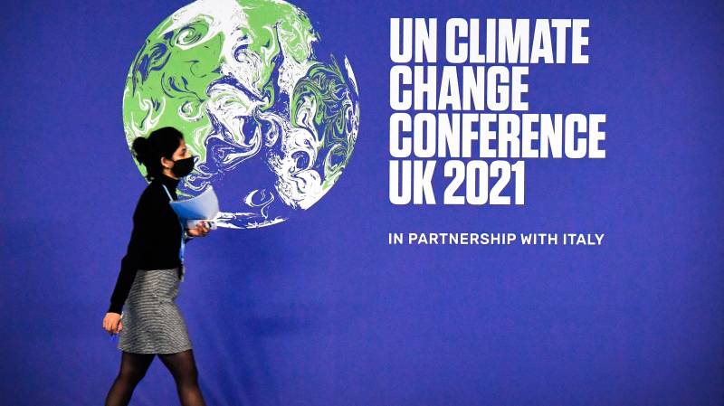 A participant walks past a COP26 UN Climate Change Conference' poster on the first day of the COP26 UN Climate Change Conference at the Scottish Event Campus (SEC) in Glasgow, Scotland. AFP