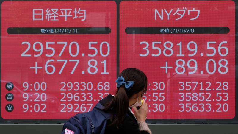 A pedestrian walks past an electronic quotation board displaying share prices of the Tokyo Stock Exchange in Tokyo on November 1, 2021. AFP