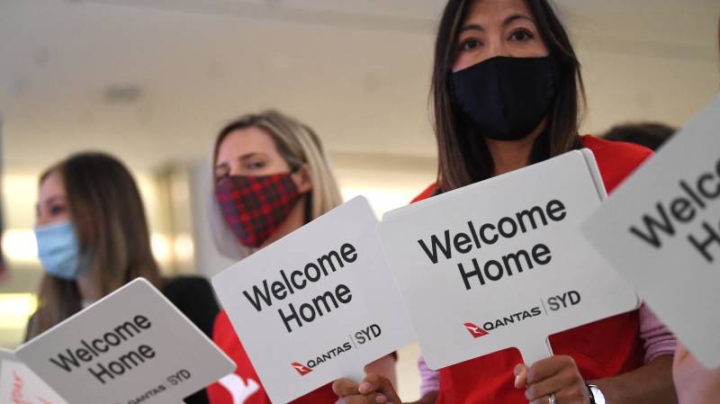 Qantas staff welcome the passengers of Los Angeles flight at the arrival gates of the Sydney International airport on November 1, 2021, after Australia relaxed mandatory quarantine restrictions. AFP