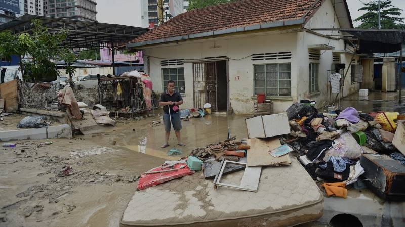 A man cleans mud from his house after it was hit by flood in Kuala Lumpur Malaysia. AFP