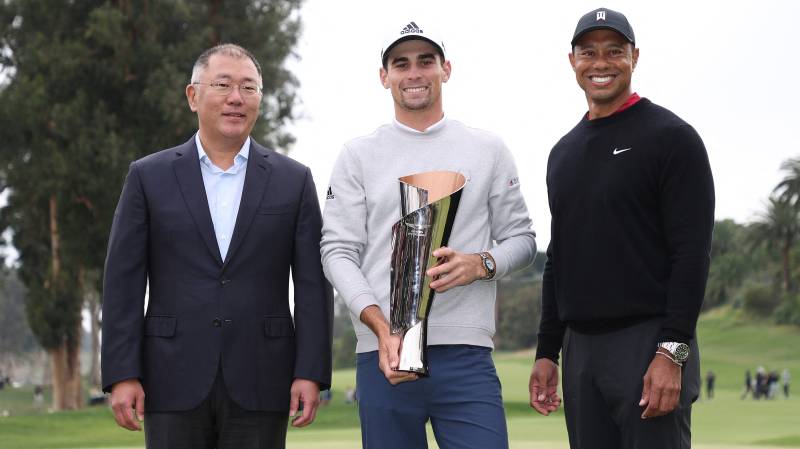 Joaquín Niemann (C) of Chile celebrates with the trophy alongside tournament host Tiger Woods (R) and Jaehoon Chang (L), President & CEO of Hyundai Motor Company. AFP