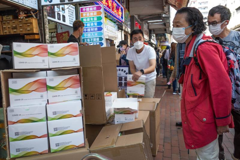 A woman (R) looks at a stall selling Covid-19 test kits in Hong Kong’s Sham Shui Po area as yet another record high number of new Covid-19 infections were recorded in the city. AFP