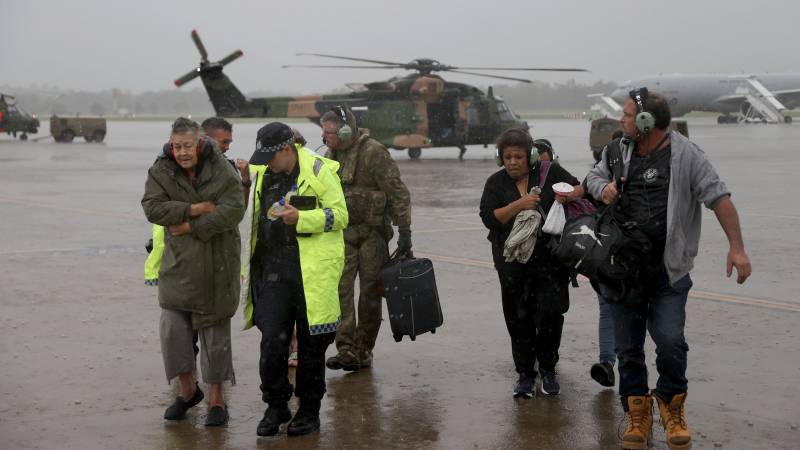 An Australian Army aircrewman and Queensland Police Service officers assisting residents rescued by an Australian Army MRH-90 Taipan helicopter aircrew from the School of Army Aviation amid flooding in south-east Queensland. AFP