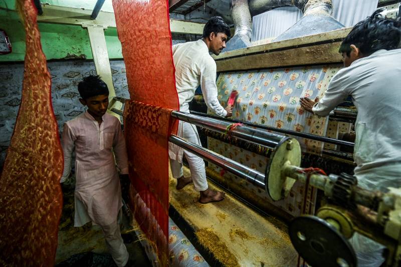 Workers give final touches to a Banarasi silk sari at a workshop in Varanasi. AFP