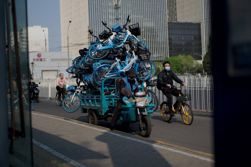 A worker for a bike rental company transports bikes on a pedicab in Beijing. AFP