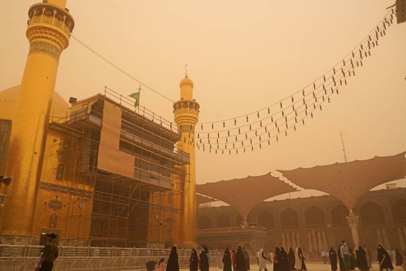 Iraqis visit the Imam Ali shrine during a sandstorm in Iraq's holy city of Najaf on May 5, 2022. 