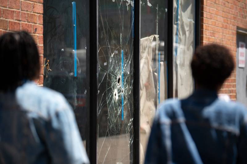 Pedestrians walk past bullet holes in the window of a store front on South Street in Philadelphia, Pennsylvania. AFP