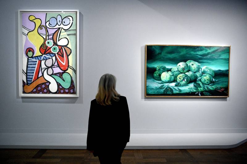 A visitor looks at artworks titled 'Grande Nature morte au gueridon' (Great Still life on pedestal) (L) by artist Pablo Picasso and 'Burlesque' (R) by artist Glenn Brown as part of the 'Les choses - Une histoire de la nature morte' (Things - A History of Still Life) exhibition at the Louvre museum in Paris. AFP