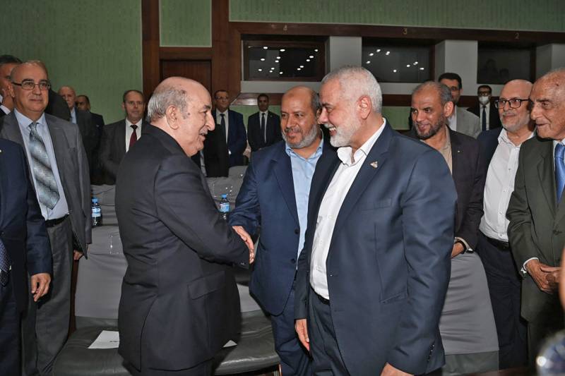 Leader of the Palestinian Hamas movement Ismail Haniyeh (C) smiling as Algerian President Abdelmadjid Tebboune (L) welcomes members of his delegation during the inter-Palestinian reconciliation meeting in the capital Algiers. AFP