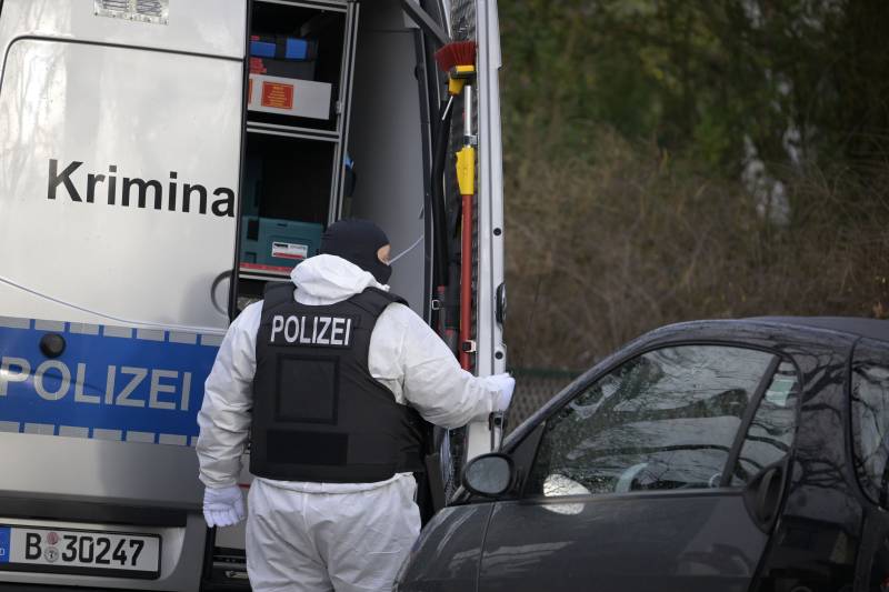 A policeman stands behind a car of the forensic experts during a raid in Berlin that is part of nationwide early morning raids against members of a far-right 