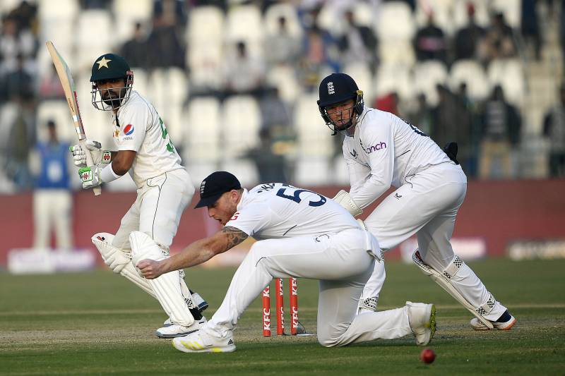 Pakistan's captain Babar Azam (L) plays a shot as England's captain Ben Stokes (C) and wicketkeeper Ollie Pope (R) watch