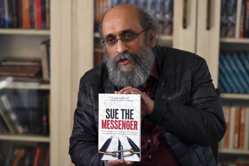 Independent Indian journalist Paranjoy Guha Thakurta holds a copy of the book 'Sue the Messenger' by authors Paranjoy Guha Thakurta and Subir Ghosh. AFP 