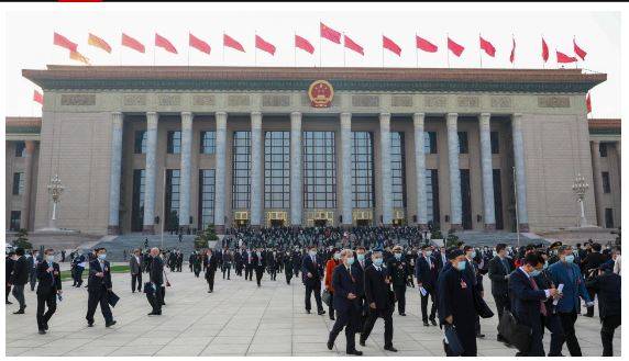 People walk in front of the Great Hall of the People on March 4, 2023, in Beijing. 