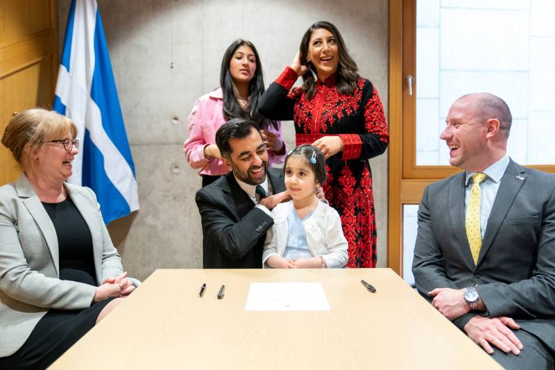 Newly elected leader of the Scottish National Party, Humza Yousaf (C) is surrounded by his wife Nadia El-Nakla (rear R), his daughter Amal (2nd R), his step-daughter Maya (rear L), proposer Shona Robison (L) and seconder Neil Gray (R), after signing the nomination form to become First Minister for Scotland, at the Scottish Parliament in Edinburgh. AFP