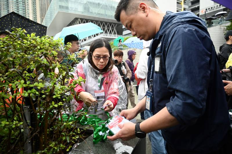 A policeman issues numbered lanyards to protesters to a group of residents to have to wear as they hold the first authorised protest and march in several years in Hong Kong against the proposal for reclamation in the district on Tseung Kwan O. AFP