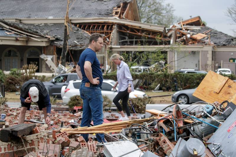 In this file photo taken on March 31, 2023, Kris French (C) and his family search through rubble for a video recorder they think captured a direct tornado strike to their business, Champs Car Wash, after a tornado damaged hundreds of homes and buildings in Little Rock, Arkansas. AFP