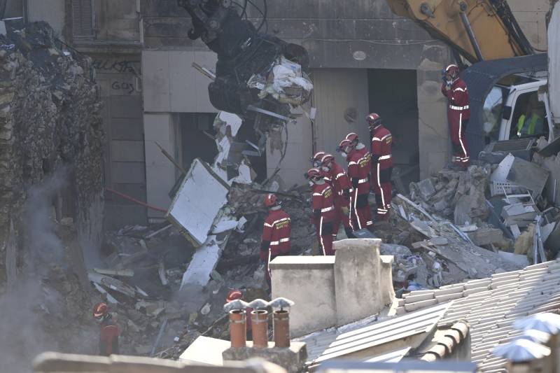 Firefighters stand aside as an excavator clears rubble at 'rue Tivoli' after a building collapsed in the street, in Marseille, southern France. AFP