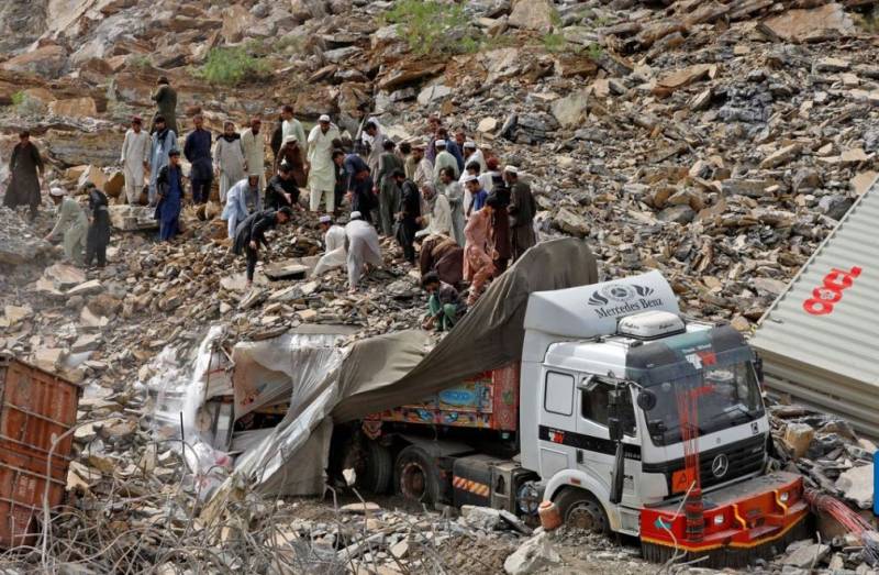 People search for survivors next to a damaged supply vehicle after a landslide close to the Torkham border on April 18, 2023.